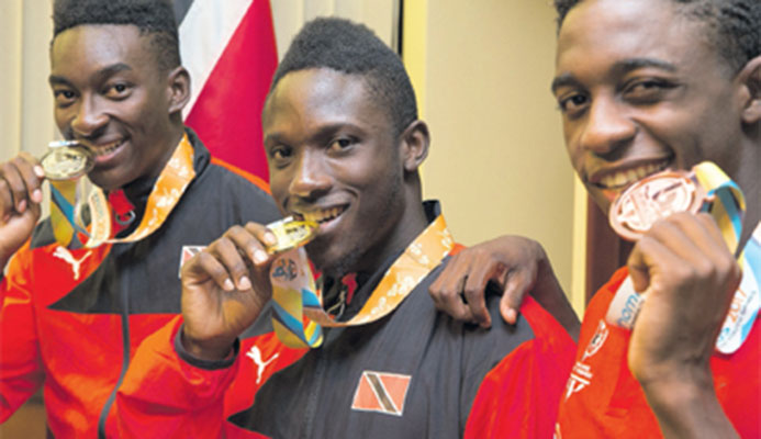 Commonwealth youth 100m sprint prince Adell Colthrust,centre, flanked by fellow countrymen Tyriq Horsford,right, and swimmer Jerron Thompson, following their arrival at the Piarco International Airport on Tuesday night. PHOTO: CA-IMAGES/ALLAN CRANE