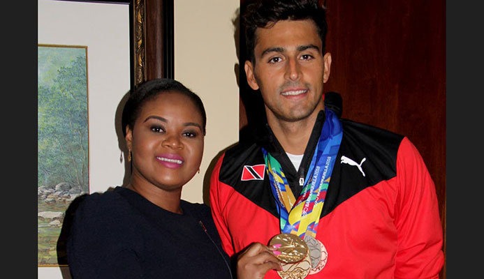 Shamfa Cudjoe, Sports Minister (left) holds one of Dylan Carter’s five medals that he earned at the CAC Games in Barranquilla, Colombia. Cudjoe met the TT swim team upon their return home at the VIP Lounge, Piarco International Airport yesterday.