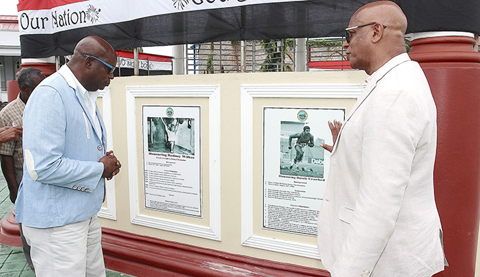 1976 Olympic Gold Medallist Hasely Crawford, left, view the Wall of Fame with San Fernando Mayor Junia Regrello after the unveiling ceremony at the Harris Promenade Bandstand in San Fernando, yesterday.  TONY HOWELL