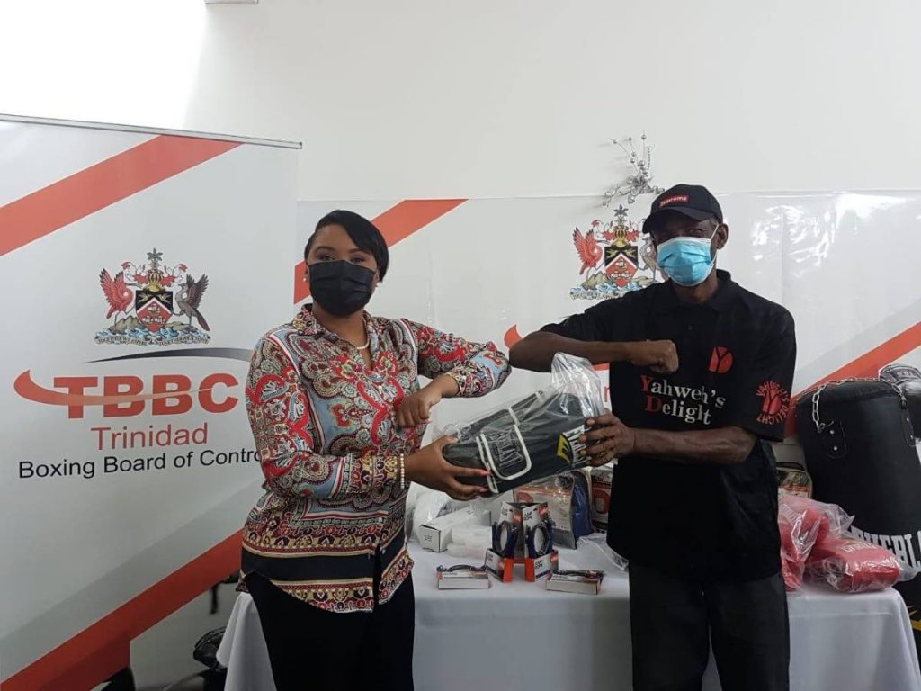 Minister of Sport and Community Development Shamfa Cudjoe, left, presents boxing gears and equipment to head coach of the Wallerfield Warriors Boxing Gym Waldron Brooks. -