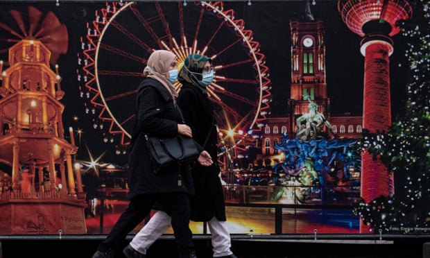 Women wearing face masks walk past the site of a traditional Christmas market in Berlin. The global study found that mask wearing was the most effective way to curb Covid infections. Photograph: John MacDougall/AFP/Getty Images