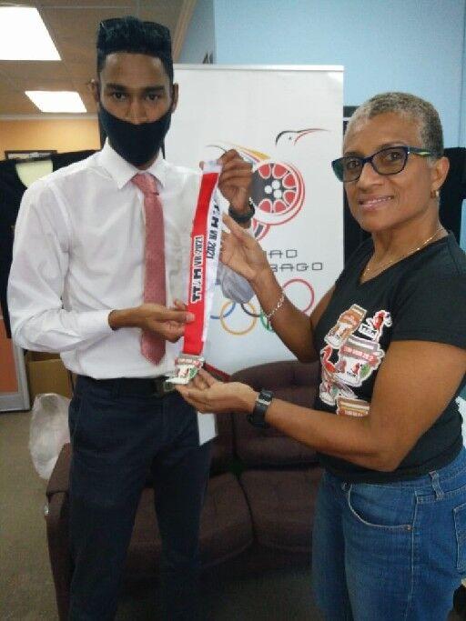 TOP TIME: Corey Joseph-Samaroo, left, receives his virtual Trinidad and Tobago International Marathon (TTIM) medal from TTIM chairperson Diane Henderson, at the T&T Olympic Committee (TTOC) office, Abercromby Street, Port of Spain, on Thursday. Joseph-Samaroo recorded the fastest time in the event, the One-A-Week runner completing 26.2 miles in three hours, 17 minutes and 38 seconds.